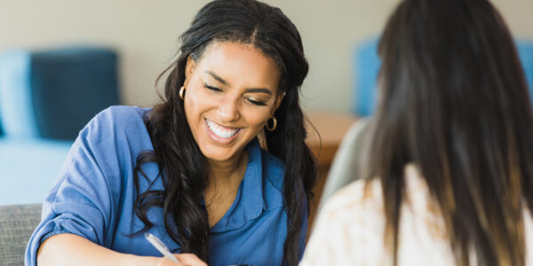 The mid adult female business owner smiles as she conducts an interview with the unrecognizable woman.